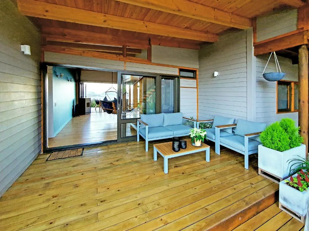 Wooden deck with blue lounge seating, potted plants, and lagoon views