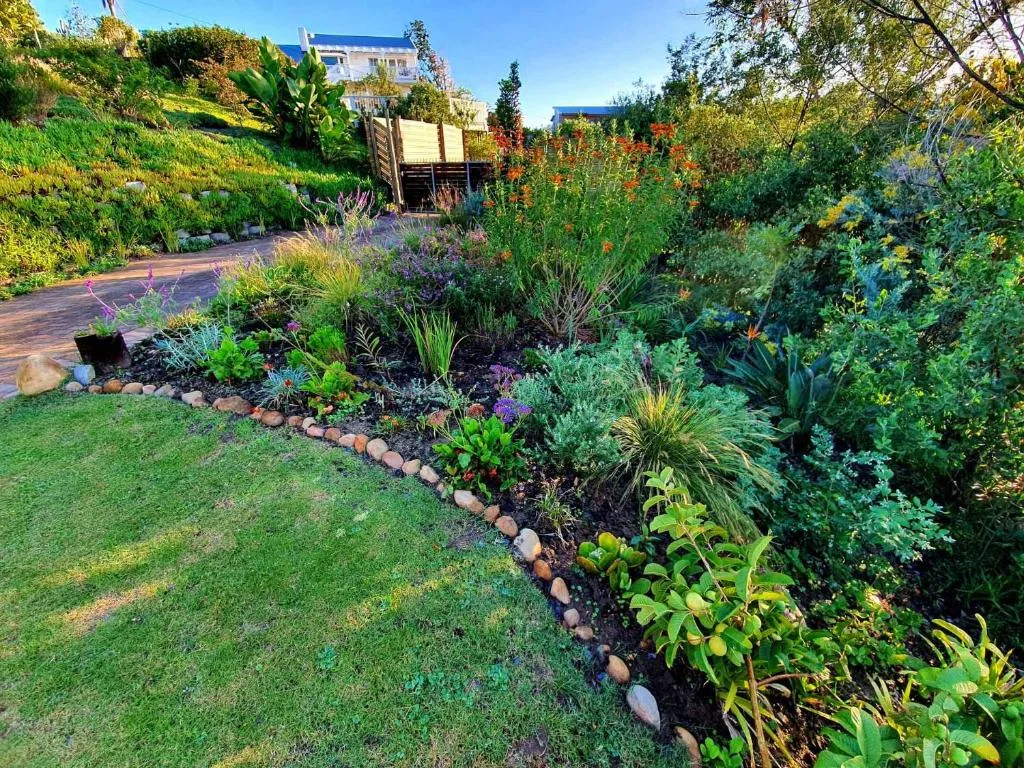 Landscaped garden with flowering plants, manicured lawn, and property buildings