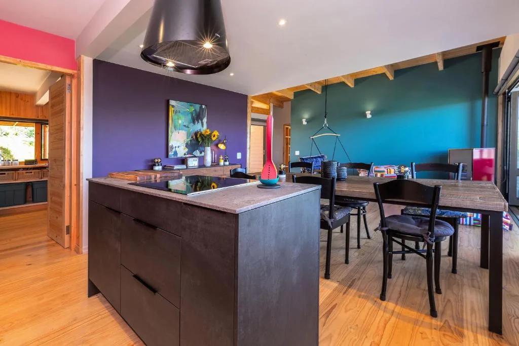 Modern kitchen with dark island, purple accent wall, and stainless steel hood