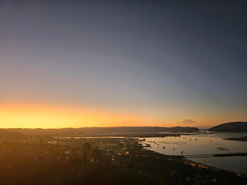 Sunset over Knysna lagoon with moored boats and coastal town lights