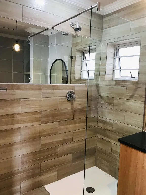 Modern walk-in shower with wood-tone tile walls and glass enclosure