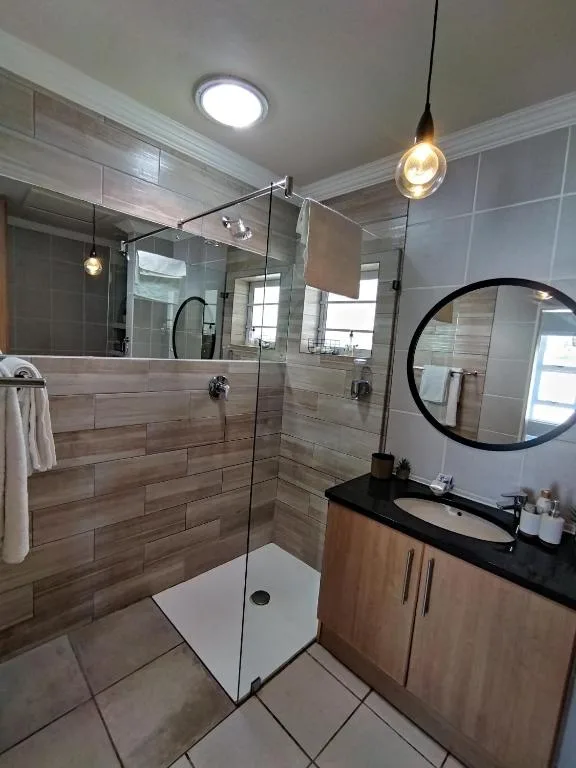 Modern bathroom with walk-in shower, black vanity, and round mirror