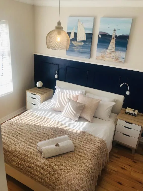 Modern bedroom with bed, nautical wall art, pendant lamp, bedside tables