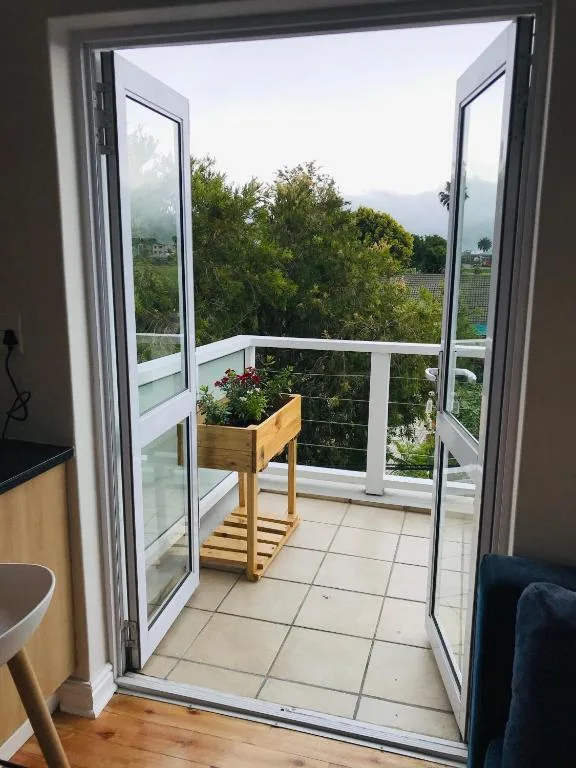 Small balcony with potted plants and mountain views beyond
