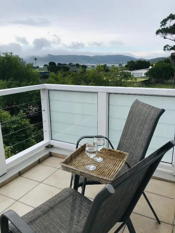 Outdoor balcony with seating and mountain view beyond green landscape