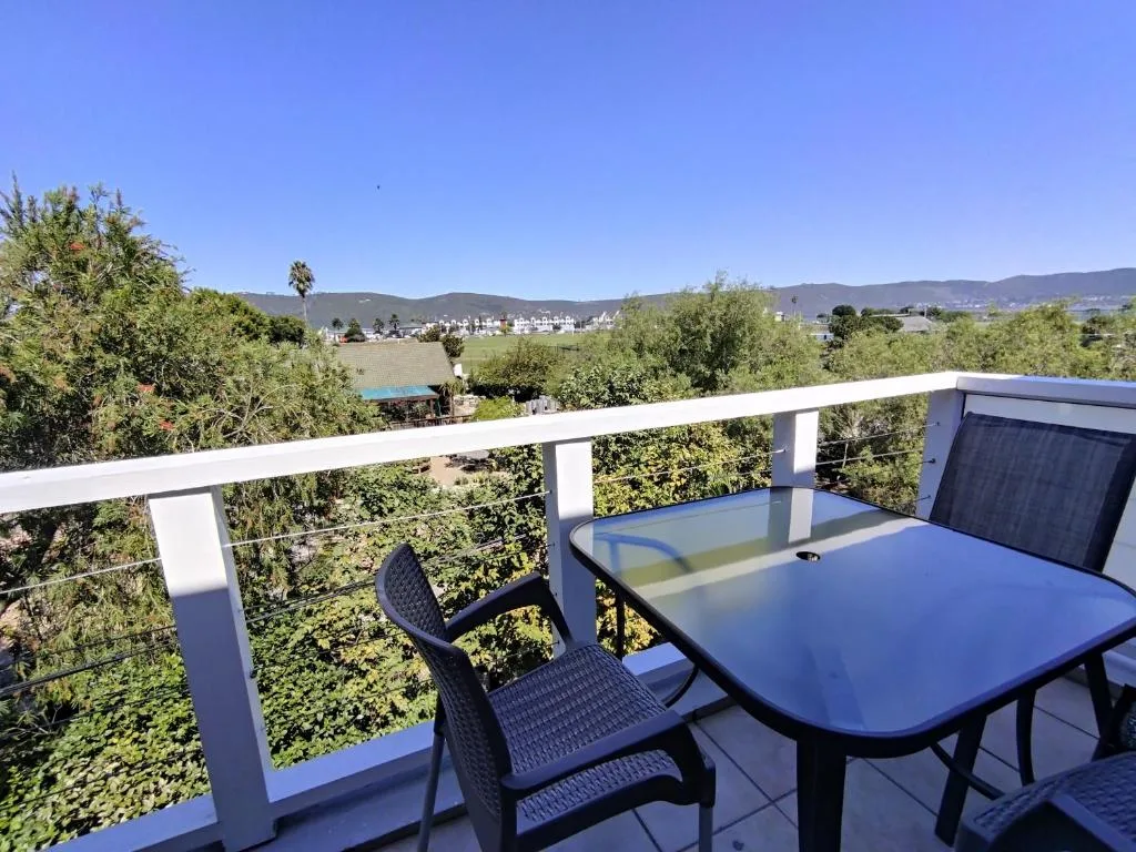 Modern balcony with blue table and chairs overlooking green valley