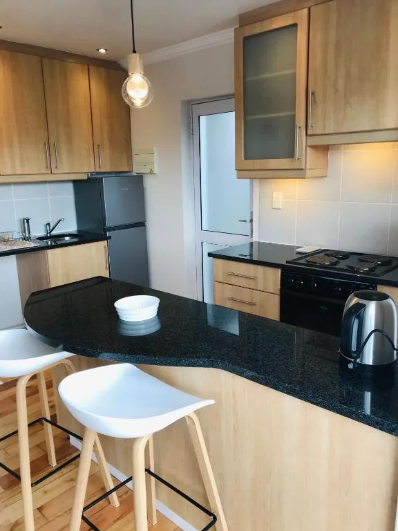 Modern kitchen with wooden cabinetry, black countertop, and stainless steel appliances