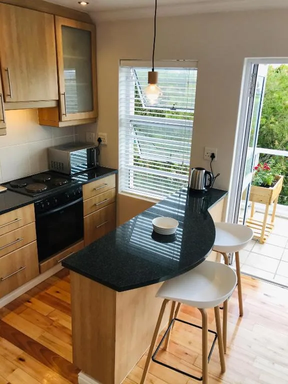 Modern kitchen with wooden cabinetry, black countertop island, and bar seating