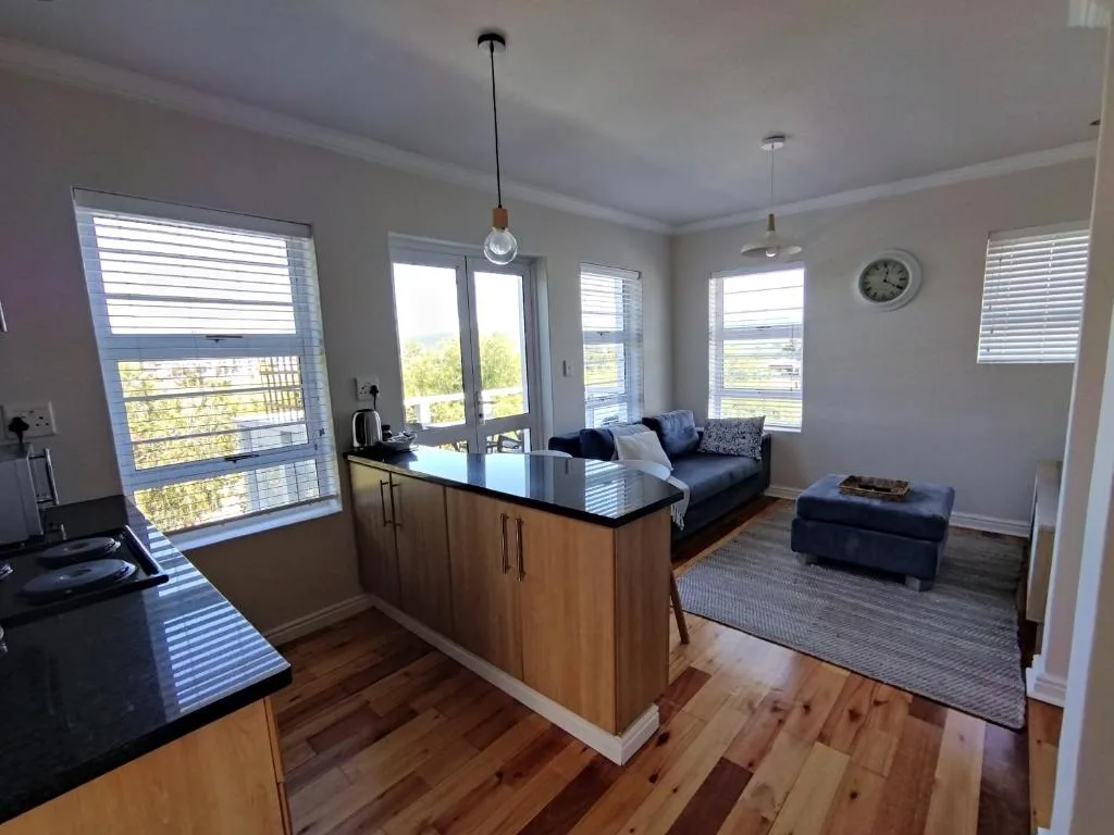 Open-plan lounge with blue sofa, wood cabinetry, large windows, and scenic views