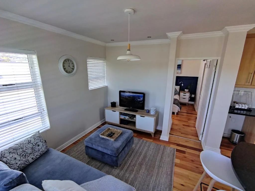 Bright open-plan lounge with blue sofa, TV unit, and modern pendant lighting