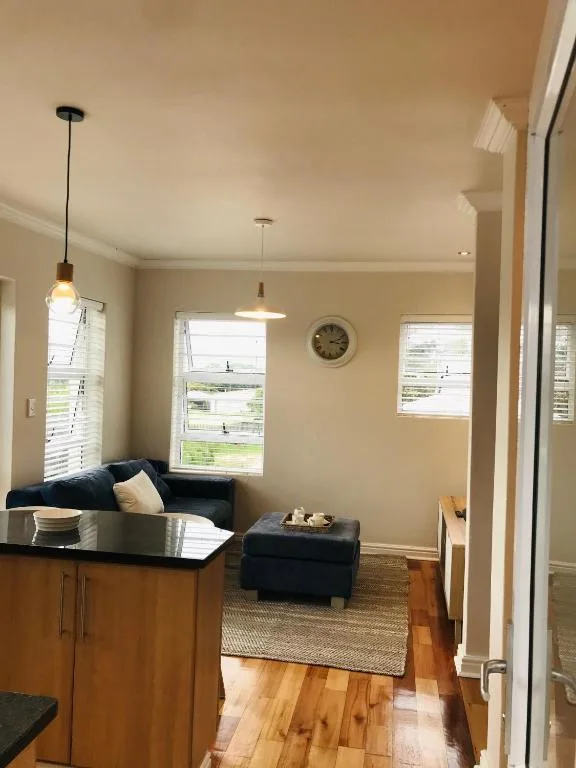 Bright living room with black sofa, pendant lighting, and garden views through windows