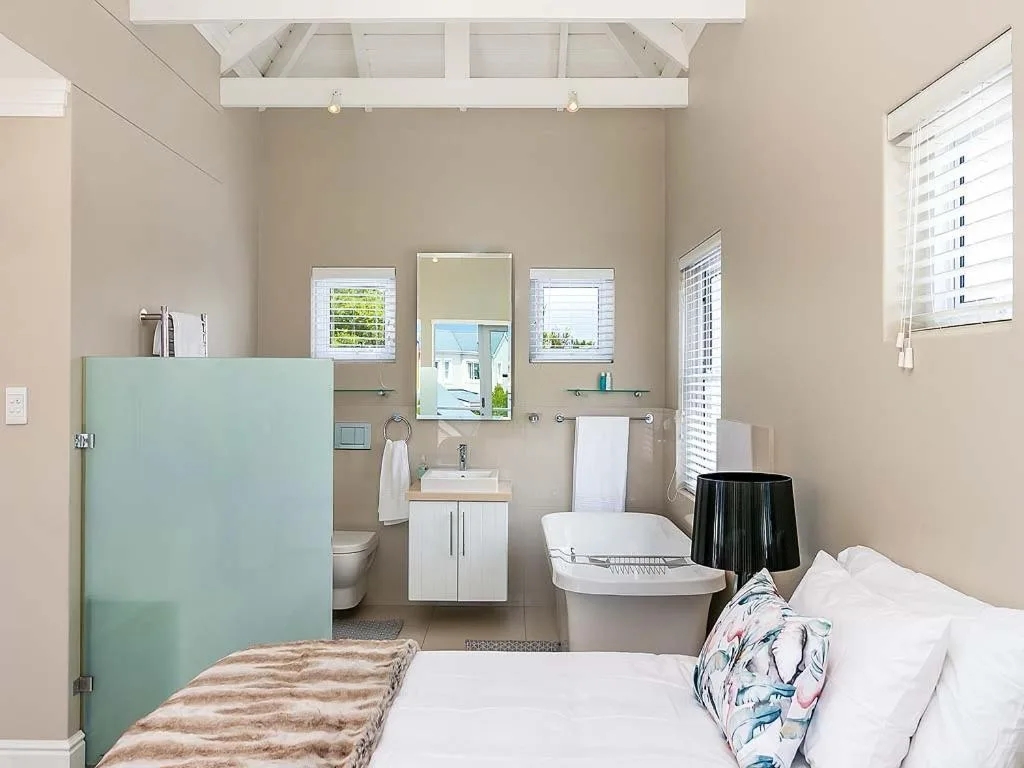 Modern bathroom with white vanity, toilet, bathtub, and large mirrors