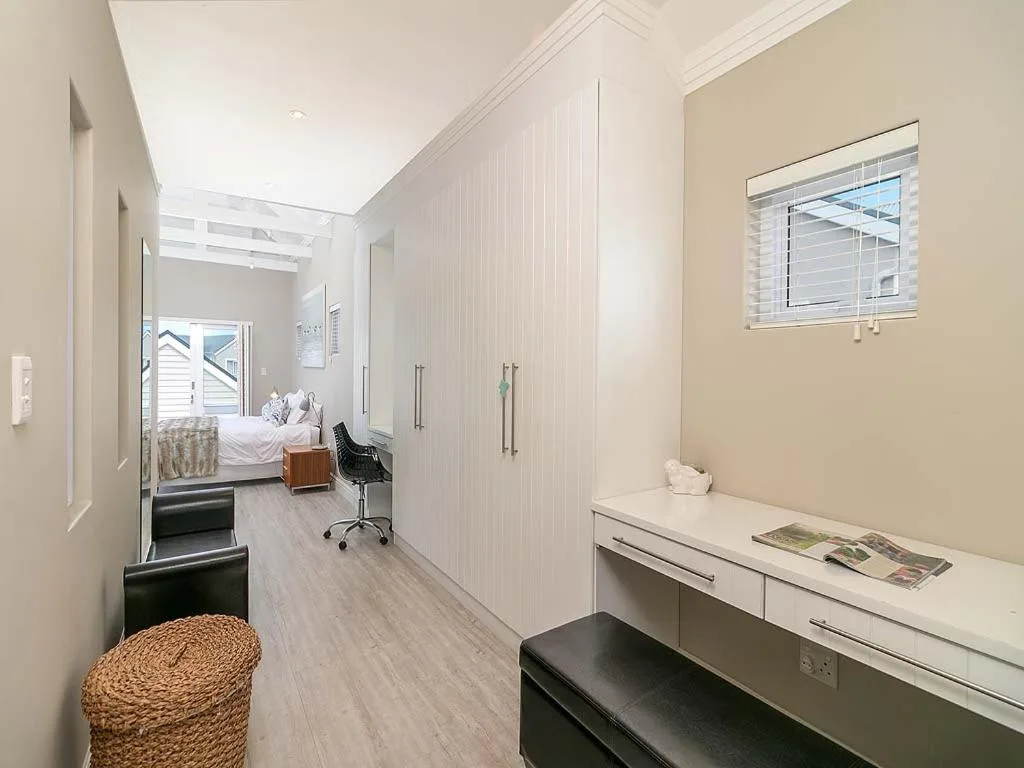 Modern bedroom with built-in wardrobes and desk area visible through open door