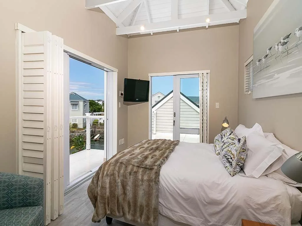 Bright bedroom with queen bed, vaulted ceiling, and glass doors opening to deck
