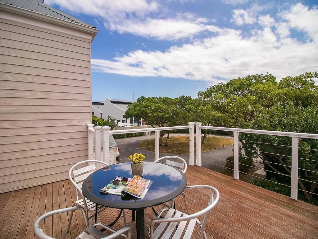 Wooden deck with outdoor seating table overlooking gardens and blue sky