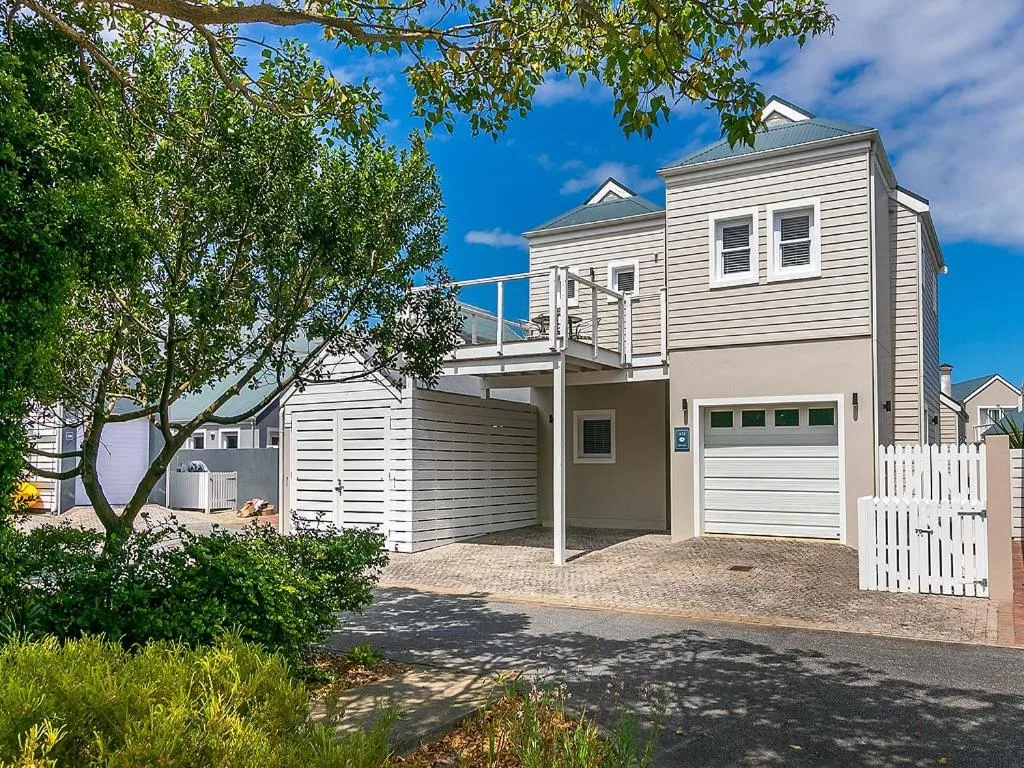 Modern white coastal home with garage, driveway, and landscaped garden