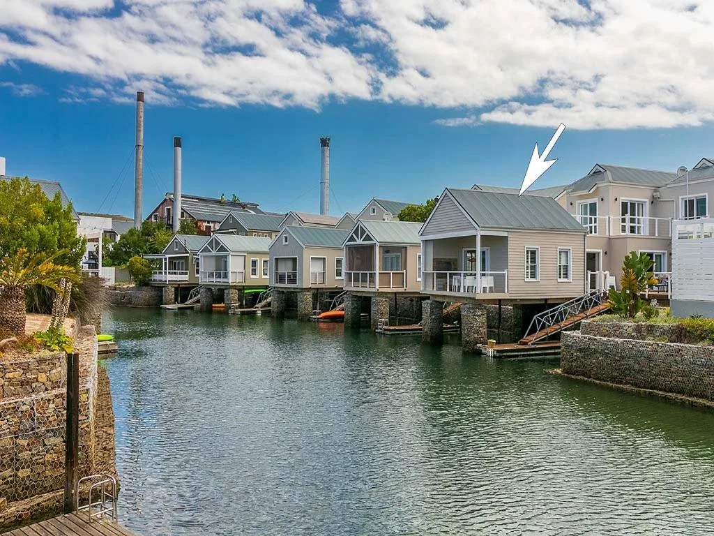 Waterfront boathouses and residential buildings along Knysna canal with blue sky
