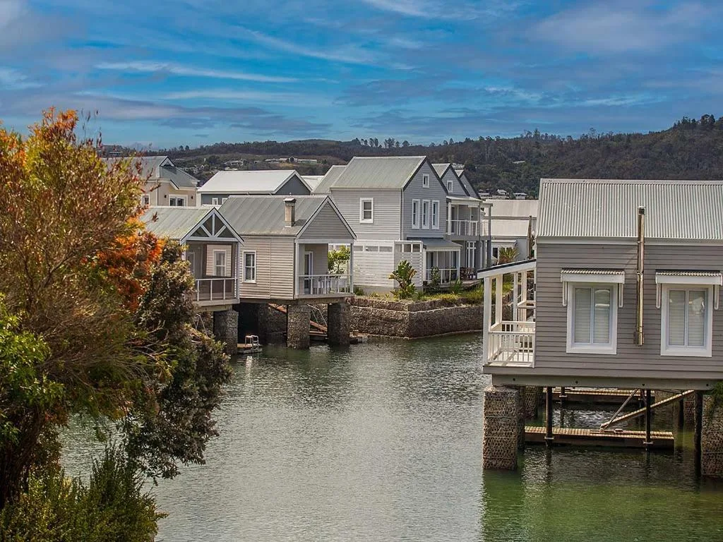 Waterfront homes on stilts along Knysna canal with mountains beyond