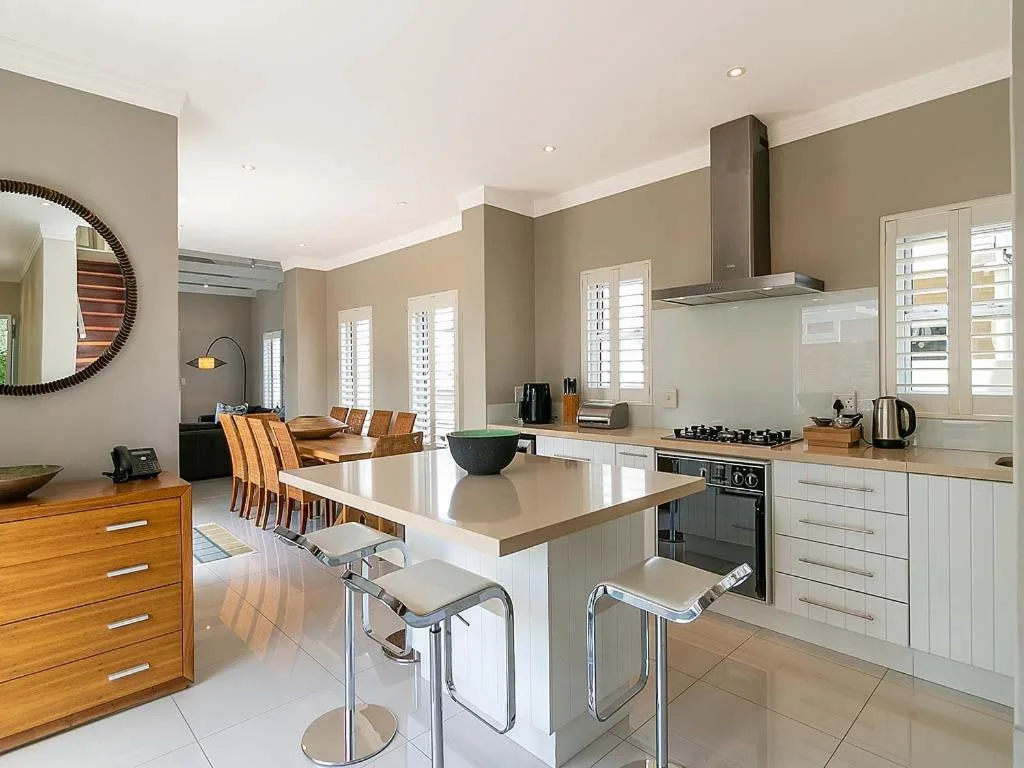 Modern open-plan kitchen with white cabinetry, island seating, and dining area