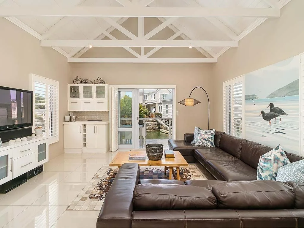 Spacious living room with brown leather sofa and coastal artwork
