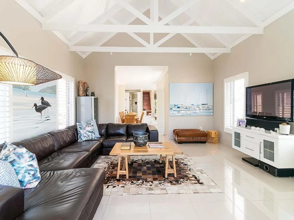 Spacious living room with black leather sectional sofa and wooden coffee table