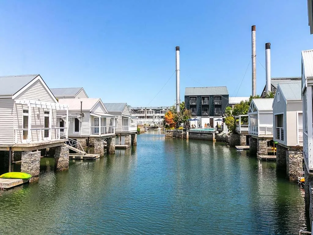 Waterfront canal with charming white cottages and industrial chimneys