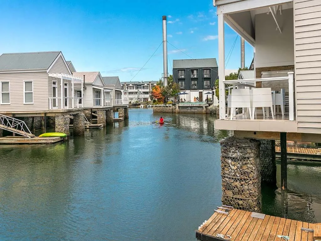 Waterfront canal with boathouses and clear blue water under sunny skies