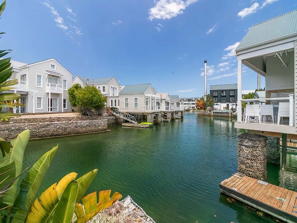 Scenic waterfront canal with white houses, boats, and tropical vegetation