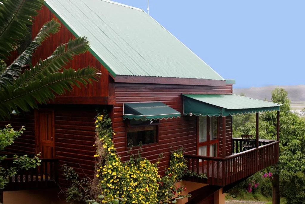 Red wooden cottage with green roof and flowering garden entrance
