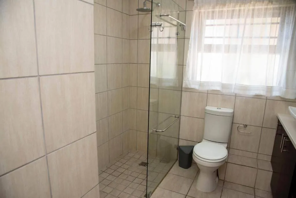 Modern bathroom with glass shower enclosure, toilet, and vanity sink