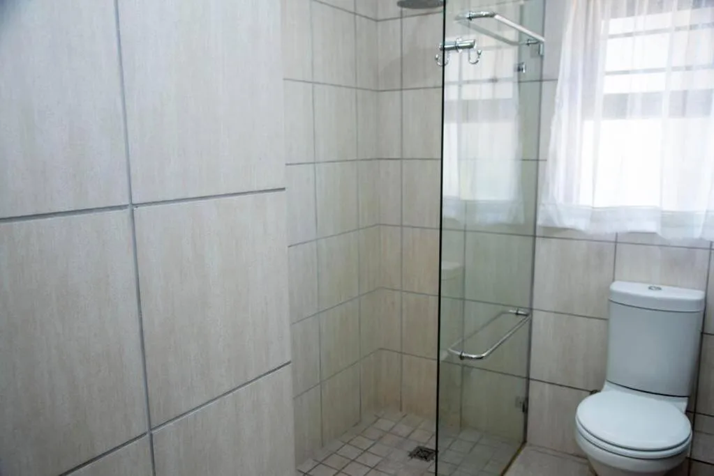 Modern bathroom with glass shower enclosure, toilet, and tiled walls