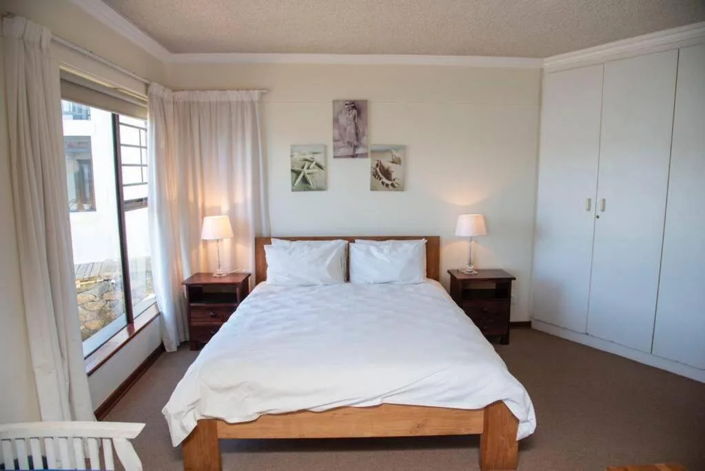 Bright bedroom with double bed, wooden furniture, and access to outdoor patio