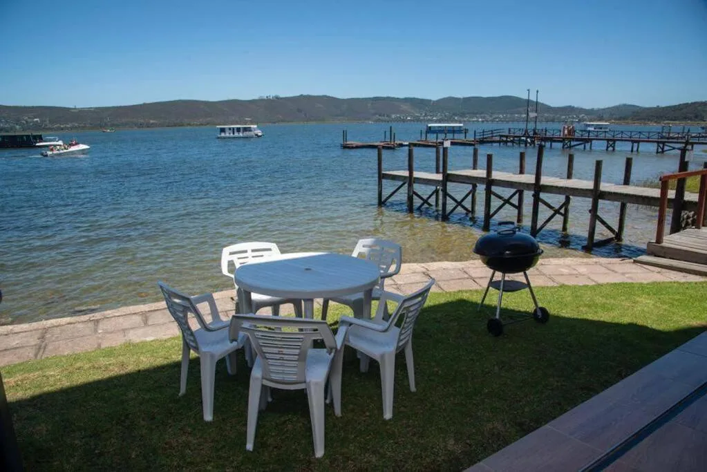 Waterfront deck with dining table, chairs, and braai overlooking lagoon