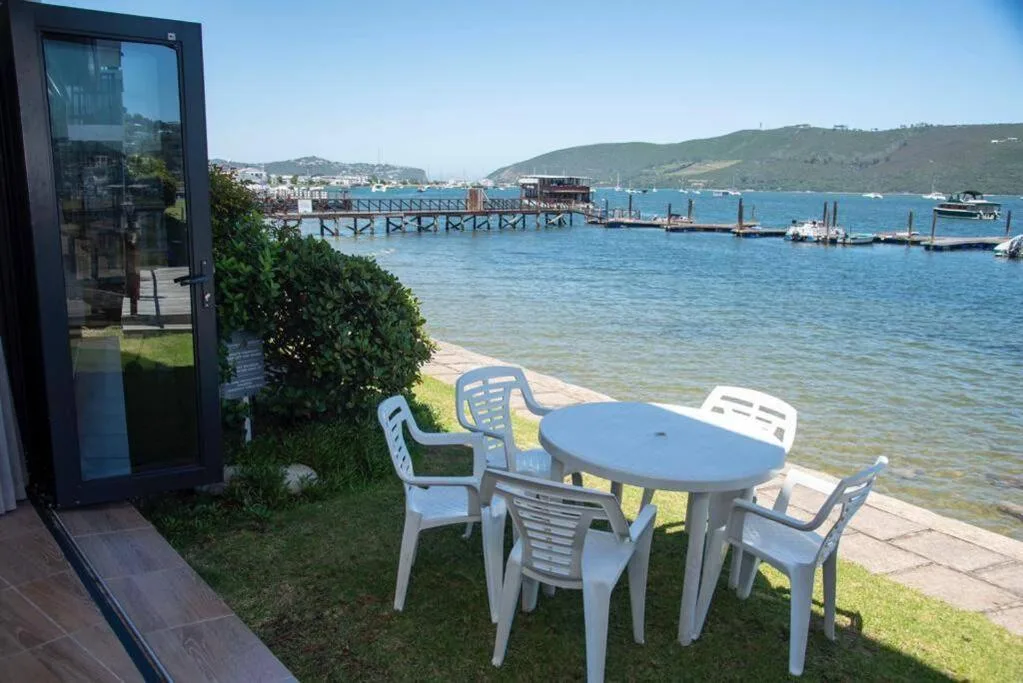 Outdoor seating area with table and chairs overlooking Knysna Lagoon and harbor