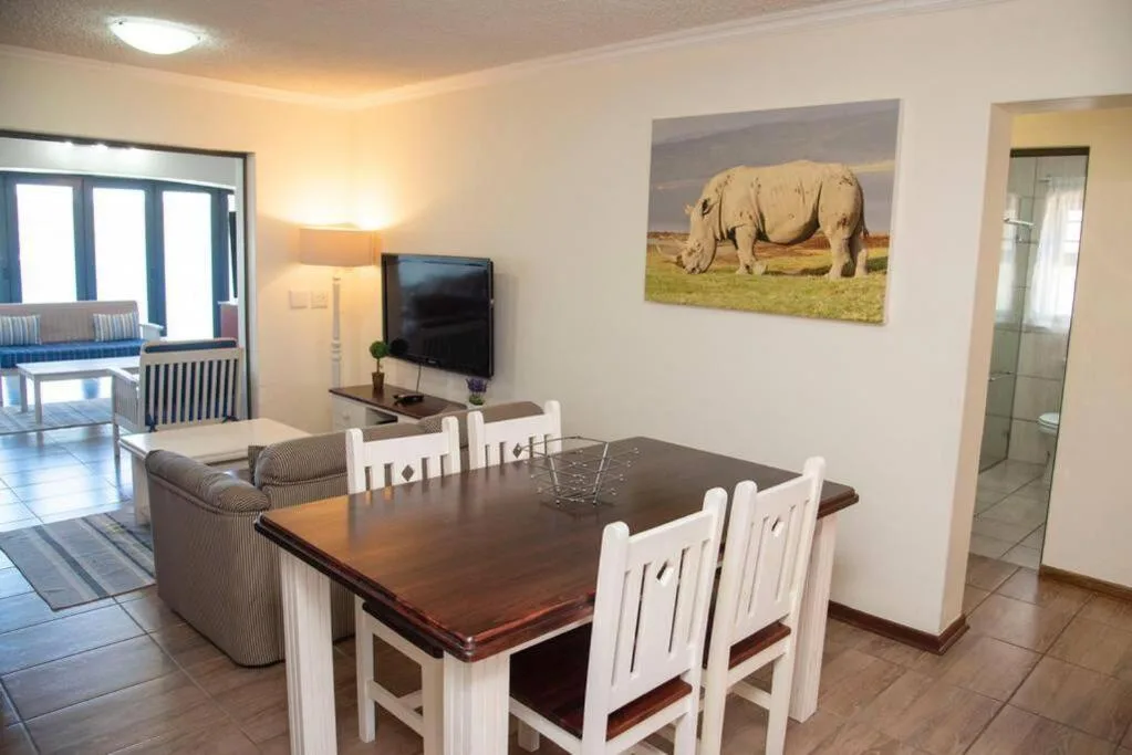Dining table with white chairs overlooking open-plan lounge area