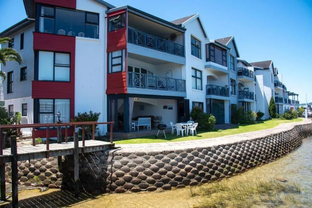 Modern waterfront apartment complex with red and white facade, beach access