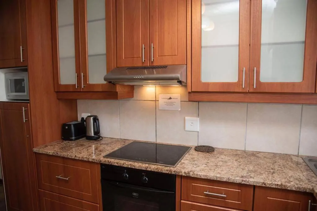 Modern kitchen with wooden cabinetry, granite countertops, and stainless steel appliances