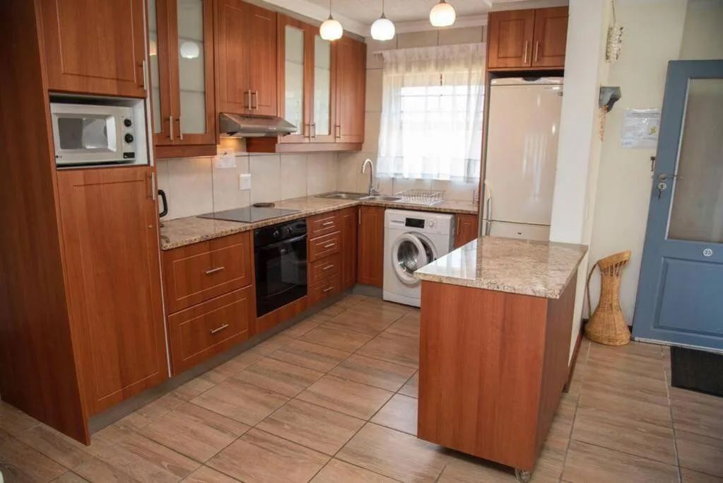 Modern kitchen with wooden cabinetry, granite counters, and island bench