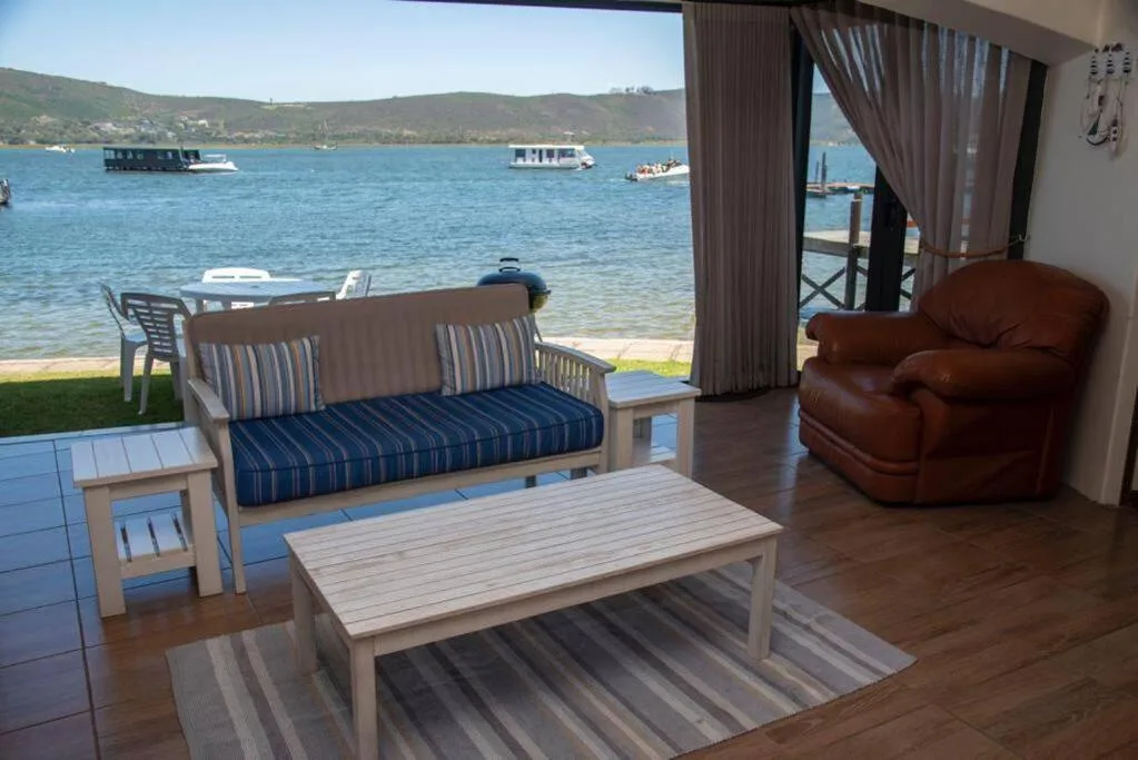 Spacious lounge with brown leather armchair and striped sofa facing lagoon view