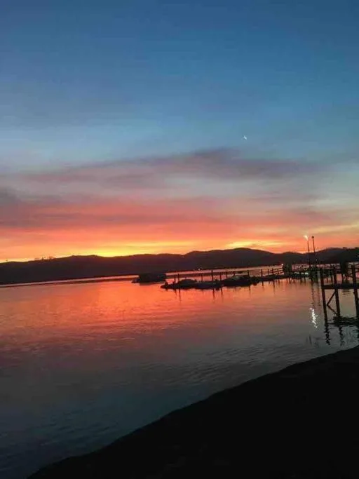 Stunning sunset over Knysna Lagoon with wooden jetty and mountains