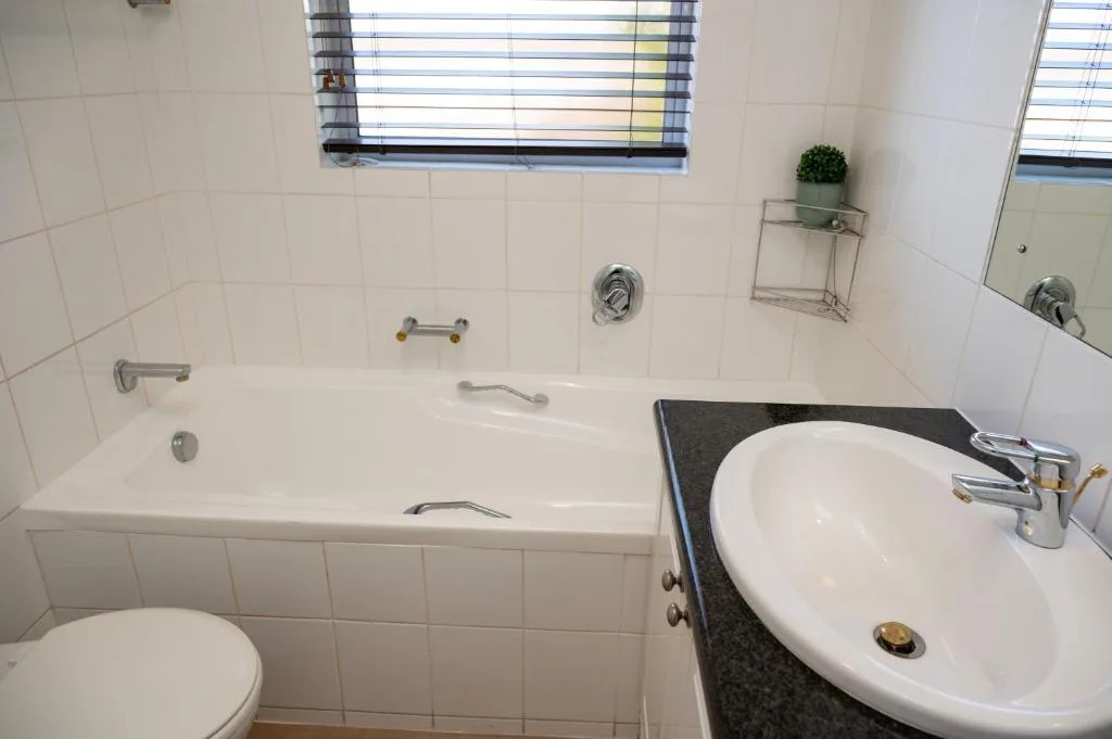 Clean bathroom with white tub, round sink, and tiled walls