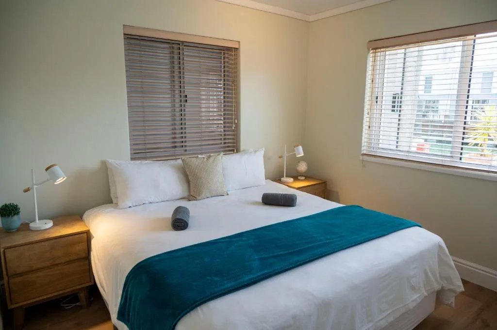 Bright bedroom with queen bed, white linens, teal runner, and bedside tables
