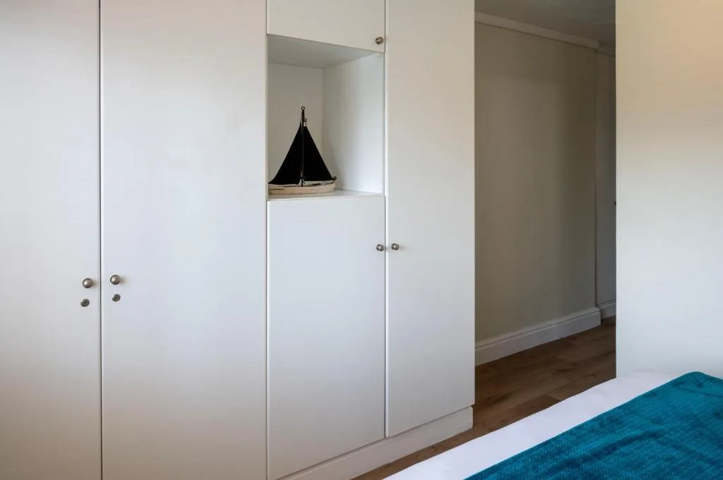 Spacious bedroom with built-in white wardrobes and decorative sailboat ornament