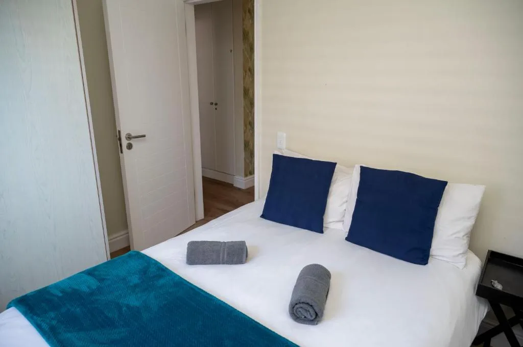 Modern bedroom with queen bed, navy pillows, and rolled towels