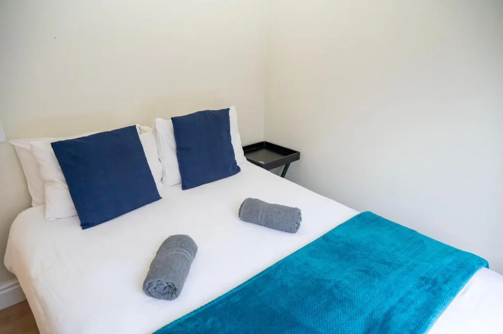 Neatly made bed with navy pillows and turquoise throw blanket