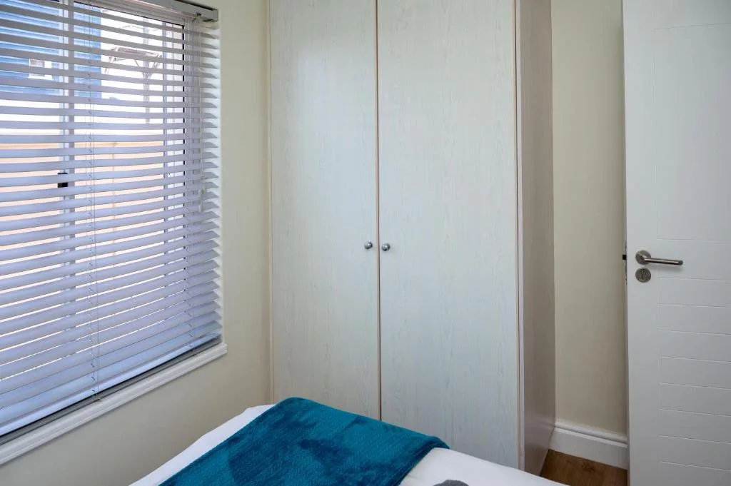 Bright bedroom with twin bed, built-in wardrobe, and horizontal blinds