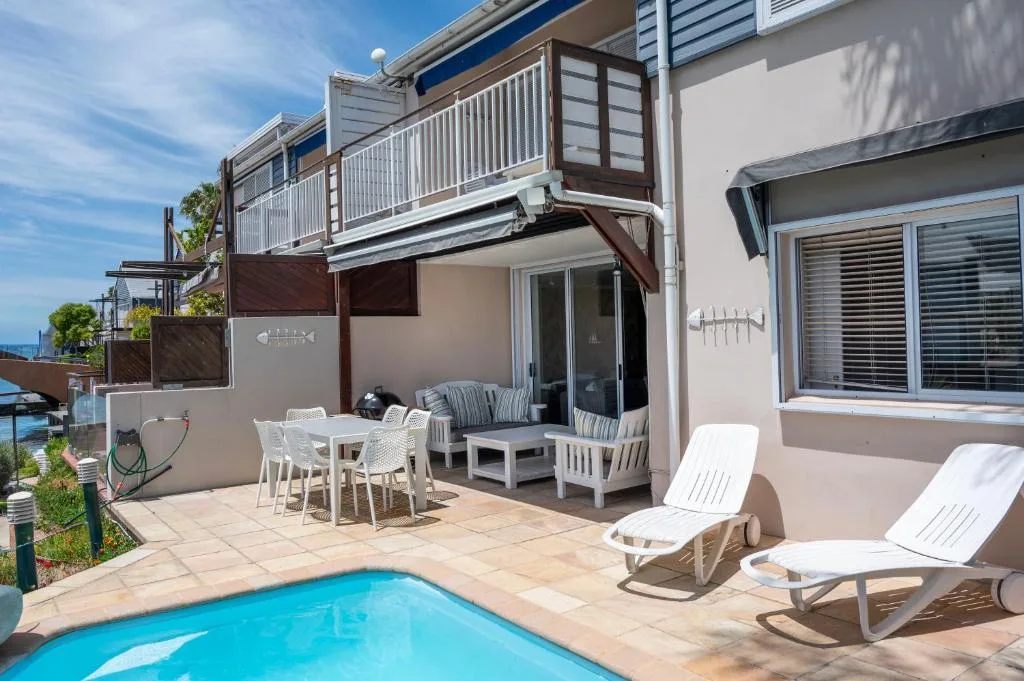 Patio with pool, loungers, dining table, and upper deck railing
