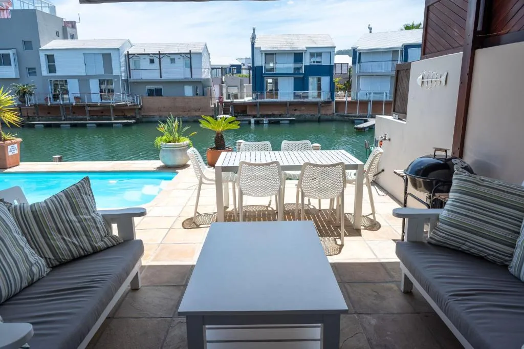Waterfront deck with seating, pool, and canal views of colorful homes
