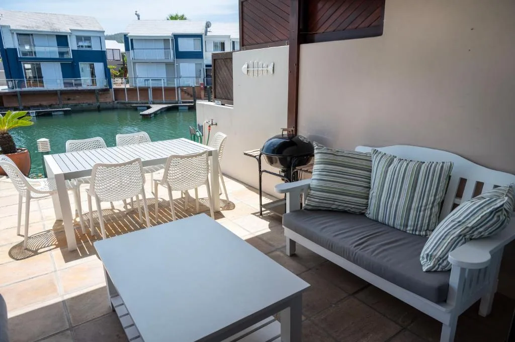 Waterfront deck with dining table, lounge seating, and lagoon views