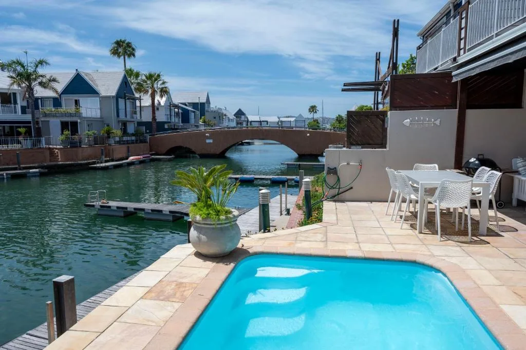 Waterfront deck with swimming pool, outdoor dining, and lagoon views
